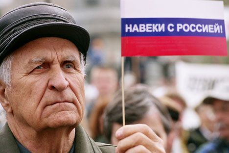 Украјински пензионер носи руску заставу на којој пише: „Заувек са Русијом!“. Извор: PhotoXpress.