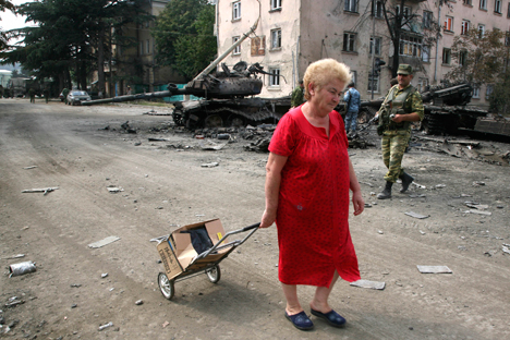 13. август 2008. у ослобођеном Цхинвалију: кућа ове пензионерке је срушена и она нема где да се врати. У позадини: изгорели тенкови грузијске војске и осетински добровољац. Извор: AP.