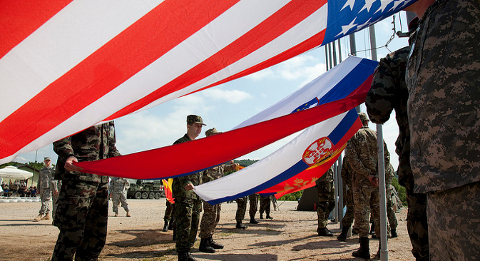 Војници осам земаља подижу заставе својих земаља на заједничкој војној вежби НАТО-а и „партнерских“ земаља одржаној у Слуњу (Хрватска) 26. маја 2012. Македонија и Србија су имале статус посматрача. Вежба је била део програма USEUCOM и њен циљ је био „постизање интероперабилности Оружаних снага САД, Ратног ваздухопловства САД, Хрватских оружаних снага и партнерских држава“. Извор: Извор: U.S. Army Europe Images.