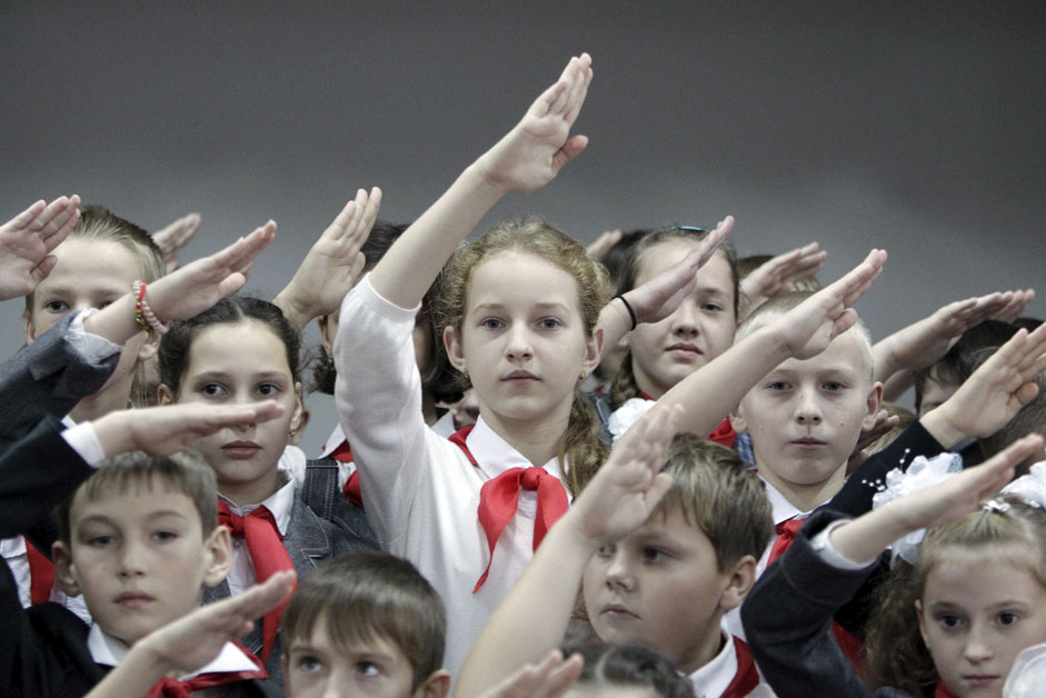 Children, wearing red neckerchiefs, a symbol of the Pioneer Organization, salute while posing for a picture during a ceremony for the inauguration of 18 newly adopted members at a local school in the southern settlement of Kazminskoye in Stavropol region, Russia, November 19, 2015. Early pro-communist youth movements, which appeared in Russia after the 1917 Bolshevik revolution, were reformed into the Pioneer Organization of the Soviet Union. While the organization lost its dominance among students in post-Soviet Russia, some educational institutions and families still carry on this tradition.