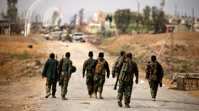 Бойцы пешмерга идут с оружием в сторону города Башика на востоке от Мосула, Ирак. 8 ноября 2016