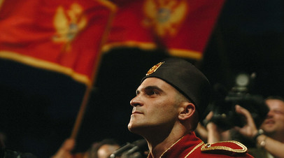 Солдат национальной гвардии на фоне флага Черногории перед зданием парламента в Подгорице