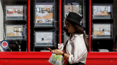 Женщина проходит мимо агентства недвижимости в Лондоне