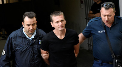 Александр Винник, сопровождаемый сотрудниками полиции, покидает суд в Салониках