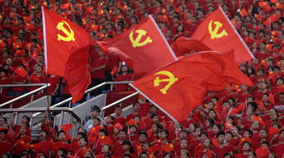 
Студенты с флагами Коммунистической партии Китая на Олимпийском стадионе в г. Чунчин, КНР