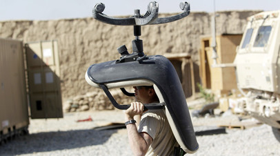 Солдат армии США несёт кресло в  фургон, Южный Афганистан