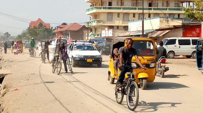 Велосипедисты и автомобилисты ездят по главной улице Увиры в провинции Южное Киву Демократической Республики Конго