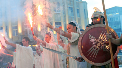 Участники костюмированного шествия в центре Скопье на фоне статуи Александра Македонского