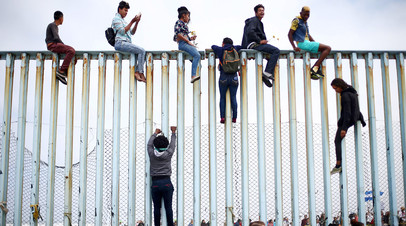 Мигранты на пограничном заборе между Мексикой и США 