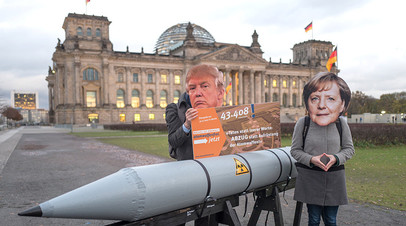 Антивоенные активисты в масках Дональда Трампа и Ангелы Меркель перед бундестагом