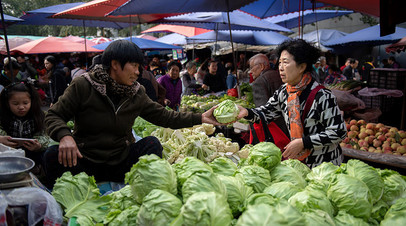 A customer (R) buys vegetables at a market in Beijing on October 16, 2018