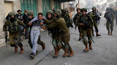 Израильские солдаты задерживают палестинца на территории Западного берега реки Иордан