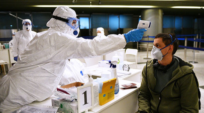 Медицинский работник измеряет температуру у пассажира в аэропорту Внуково