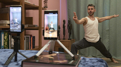 Инструктор проводит трансляцию и видеозапись урока йоги у себя дома в Санкт-Петербурге
