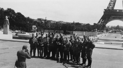 Военнослужащие люфтваффе позируют фотографу на фоне Эйфелевой башни в Париже. В центре стоит девушка — возможно, сотрудница оккупационной администрации. 1940 год