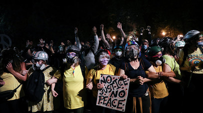 Группа матерей стоит между протестующими и федеральными силовиками во время акции протеста в Портленде