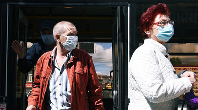 Горожане в медицинских масках выходят из автобуса на остановке общественного транспорта в Новосибирске