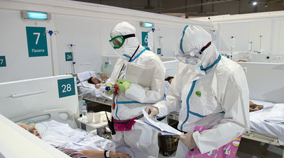 Медицинские работники во время осмотра пациента во временном госпитале для больных COVID-19, развёрнутом в ледовом дворце «Крылатское»