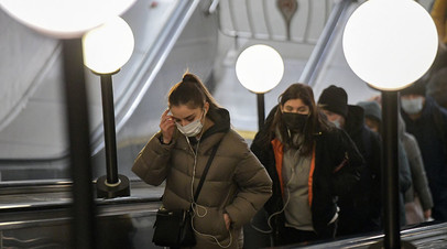 Пассажиры в защитных масках на эскалаторе в московском метрополитене