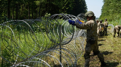 Литовские военнослужащие устанавливают колючую проволоку на границе с Белоруссией