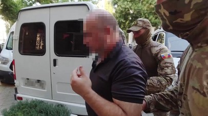 Сотрудники ФСБ сопровождают задержанного участника ячейки запрещённой международной террористической организации «Хизб ут-Тахрир»