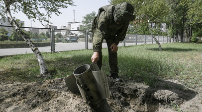 Российский военнослужащий рядом с боеприпасом, выпущенным ВСУ по территории Запорожской АЭС