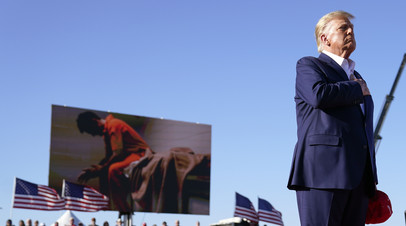 Дональд Трамп во время предвыборного митинга в Техасе. На фоне — плакат, посвящённый заключённым, арестованным за участие в штурме Капитолия в январе 2021 года