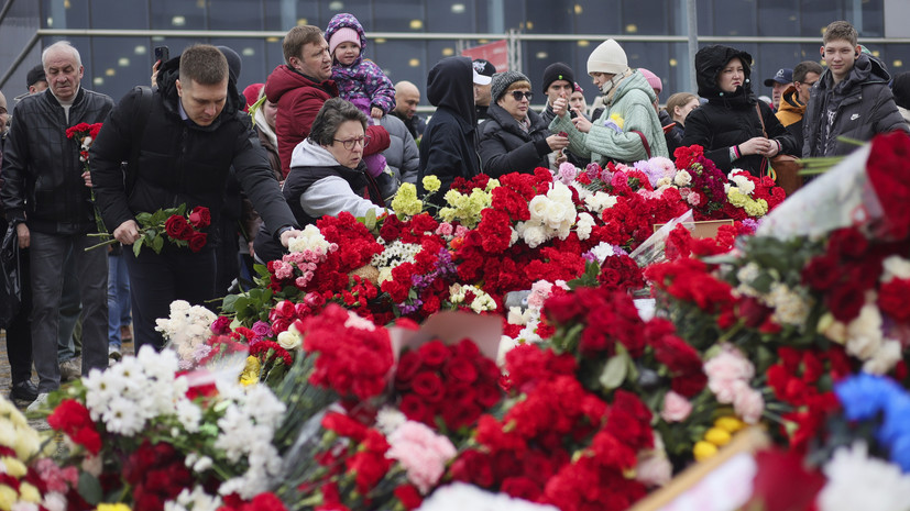 Люди несут цветы к стихийному мемориалу у «Крокус Сити Холла»